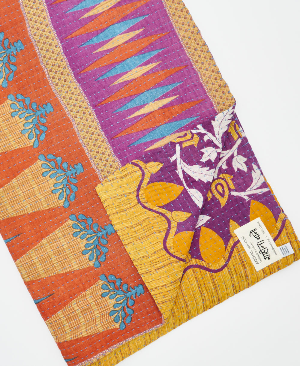 kantha quilt throw with a tag featuring the hand-stitched signature of the maker