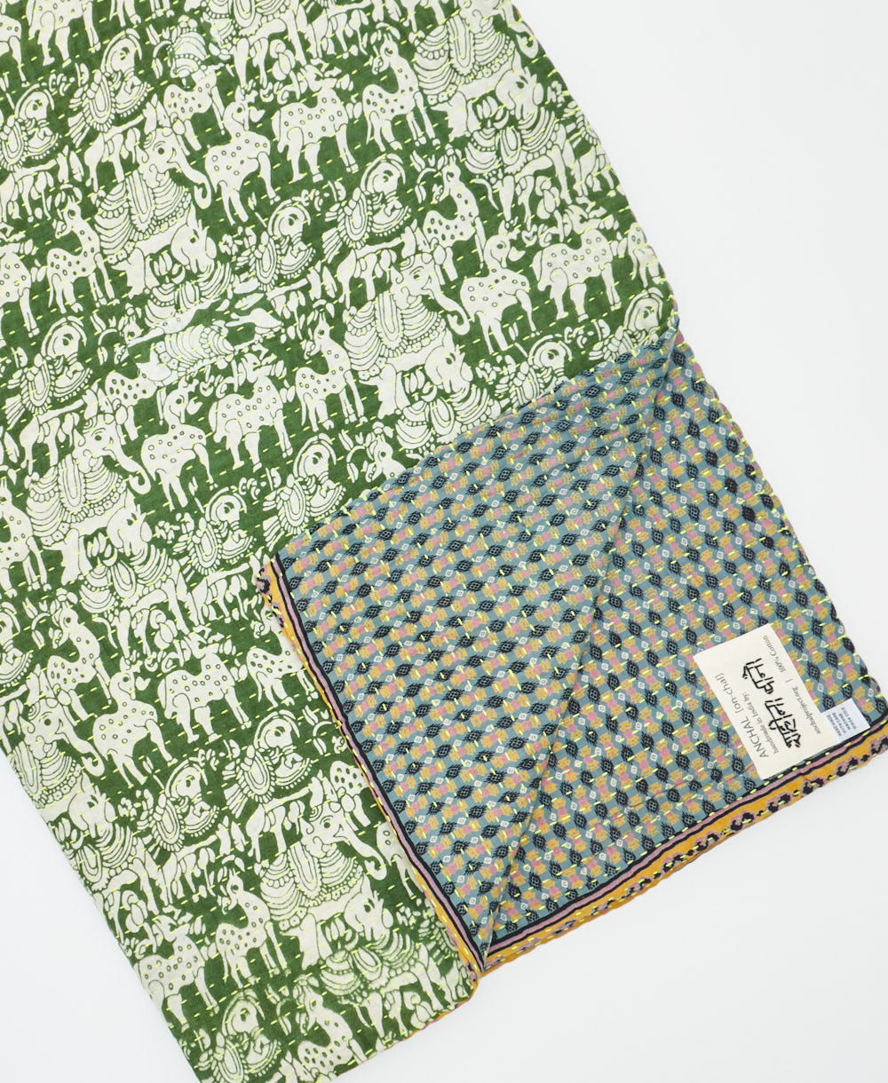 kantha quilt throw with a tag featuring the hand-stitched signature of the maker