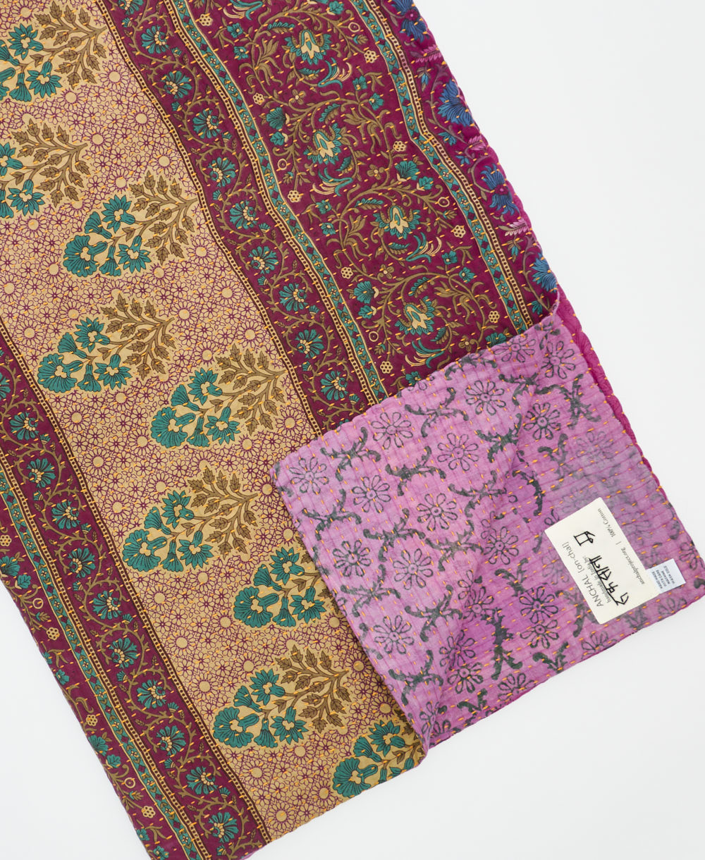 kantha quilt throw with a tag featuring the hand-stitched signature of the maker