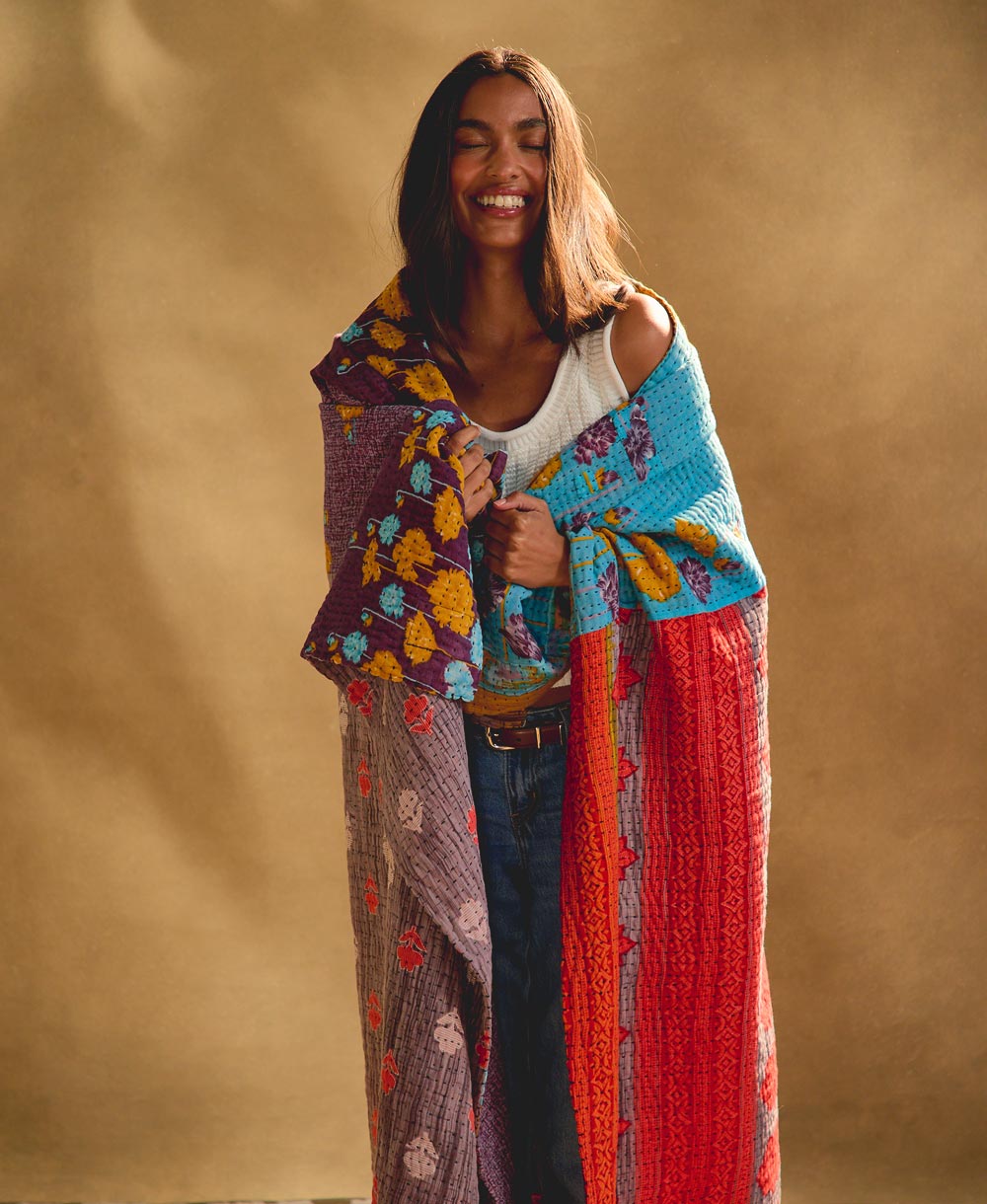 woman wrapped in colorful kantha quilt handmade in India by all women artisans
