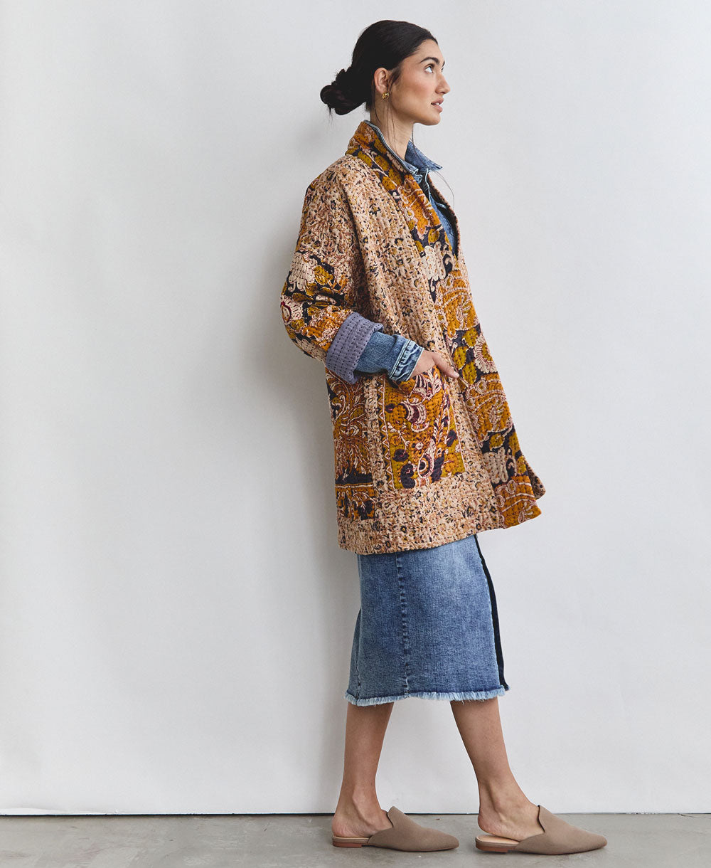 woman wearing a denim midi skirt and a quilted jacket in mustard yellow and navy hues