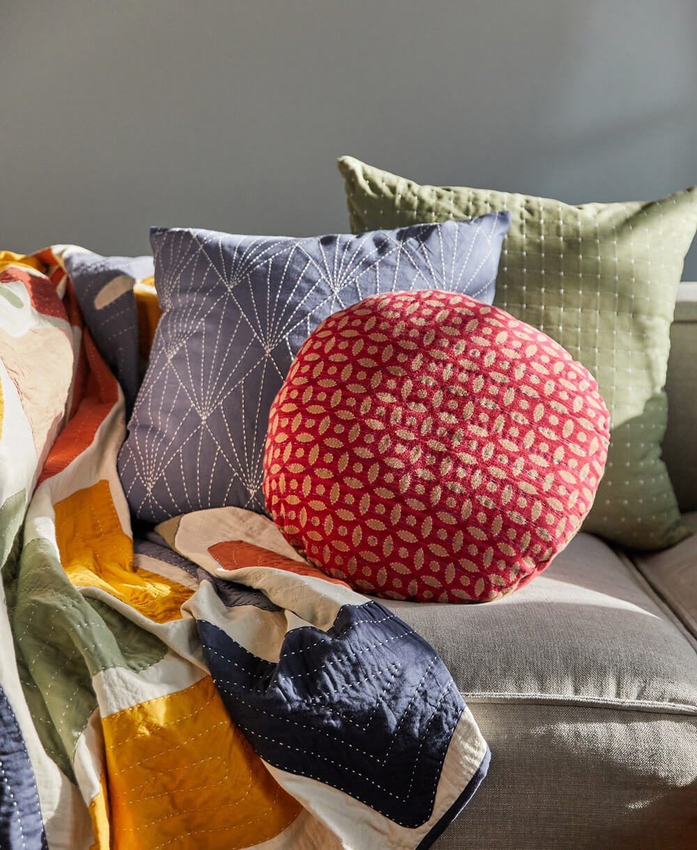 Colorful pillows and a blanket on a sofa against a neutral wall
