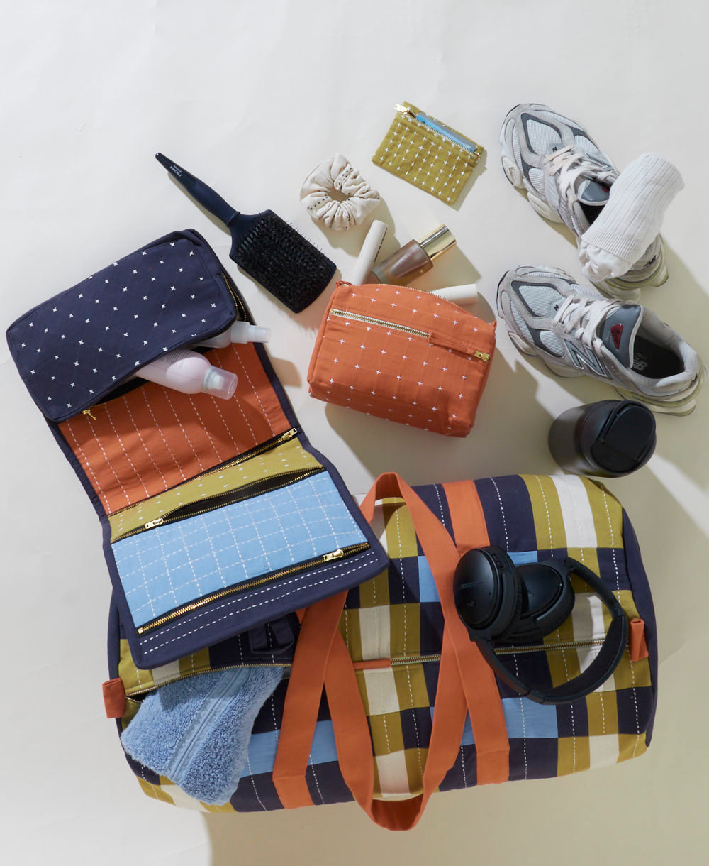 Colorful travel bag with various items on a light surface