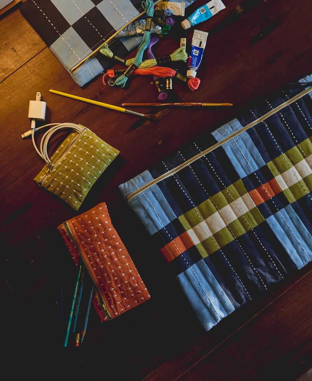 quilted plaid laptop sleeve sitting on wooden surface with other matching pouches in bold colors