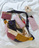 Colorful patchwork fanny pack with various items on a white fabric background