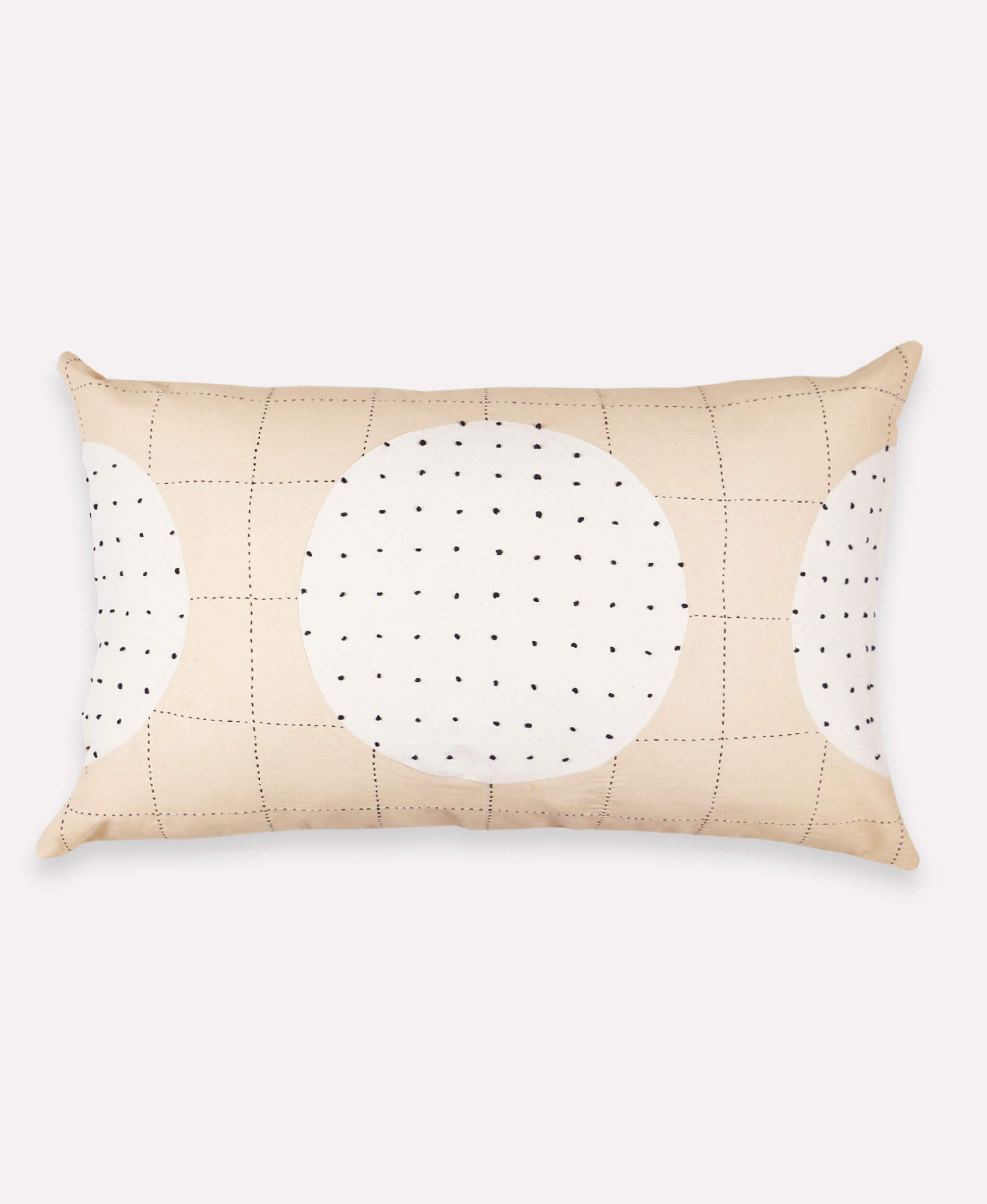 Beige pillow with a circular cutout featuring black dots on a white background