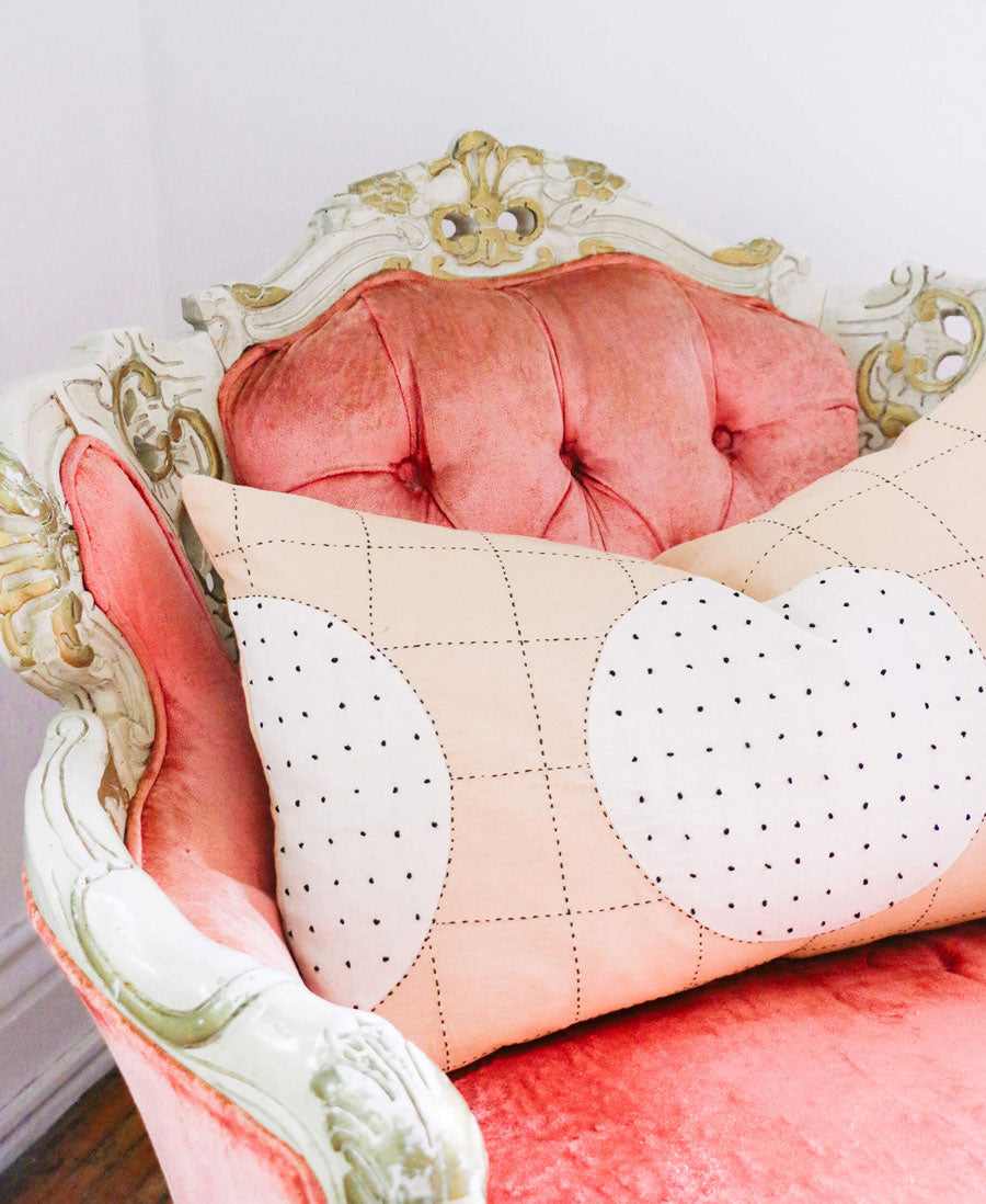 Decorative pillow with heart patterns on a pink chair with gold accents