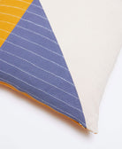 Close-up of colorblock throw pillow with blue, yellow, and white geometric pattern on a white background