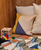 Colorful pillows and a wooden block set on a wooden floor against a wooden wall