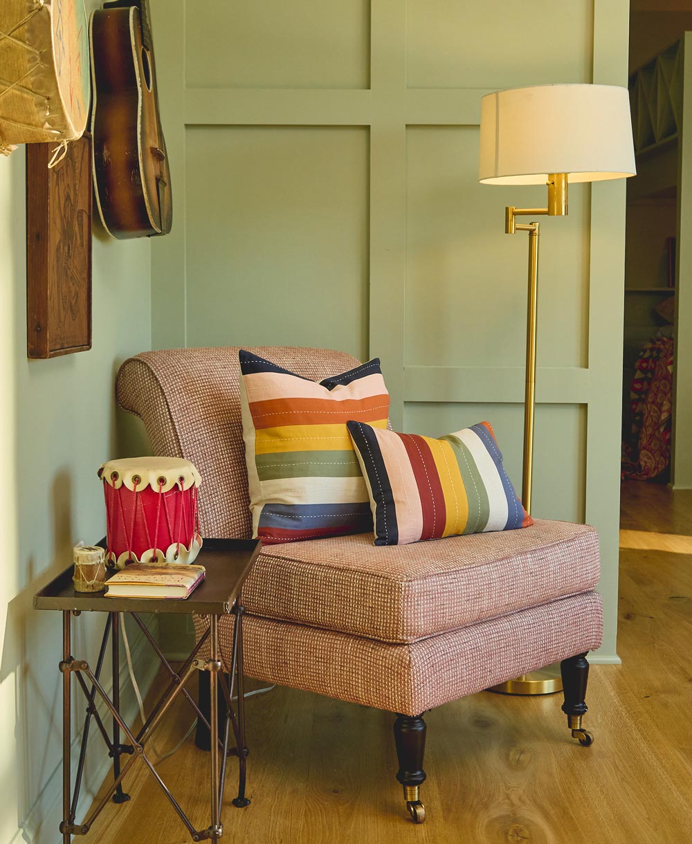 Cozy living room corner with a brown armchair, colorful pillows, and a lamp
