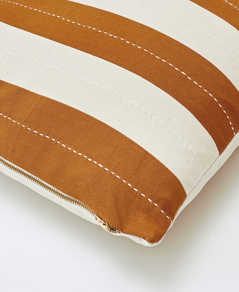 Close-up of a cushion with brown and white stripes on a light background