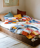 Bed with colorful bedding and pillows in a room with a map on the wall.