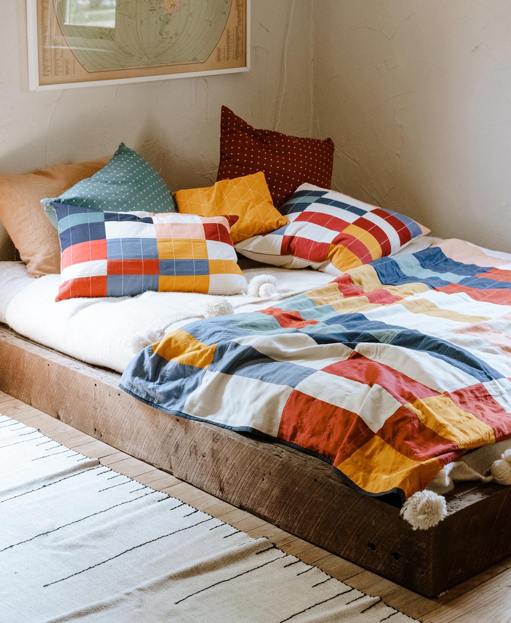 Bed with colorful bedding and pillows in a room with a framed picture on the wall