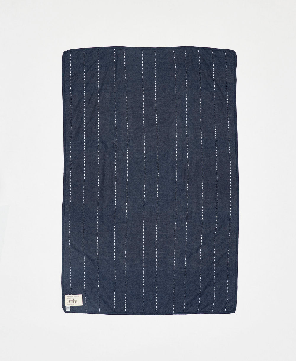 Navy blue quilt with white pinstripes on a light gray background
