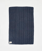 Navy blue quilt with white pinstripes on a light gray background