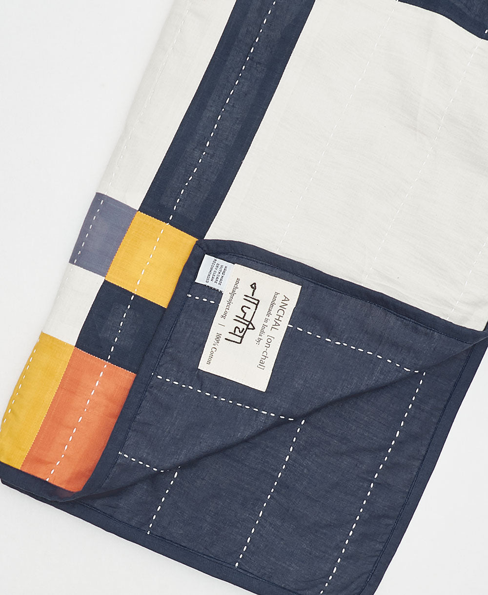 artisan-signed brand tag on multi-plaid baby quilt handmade in India