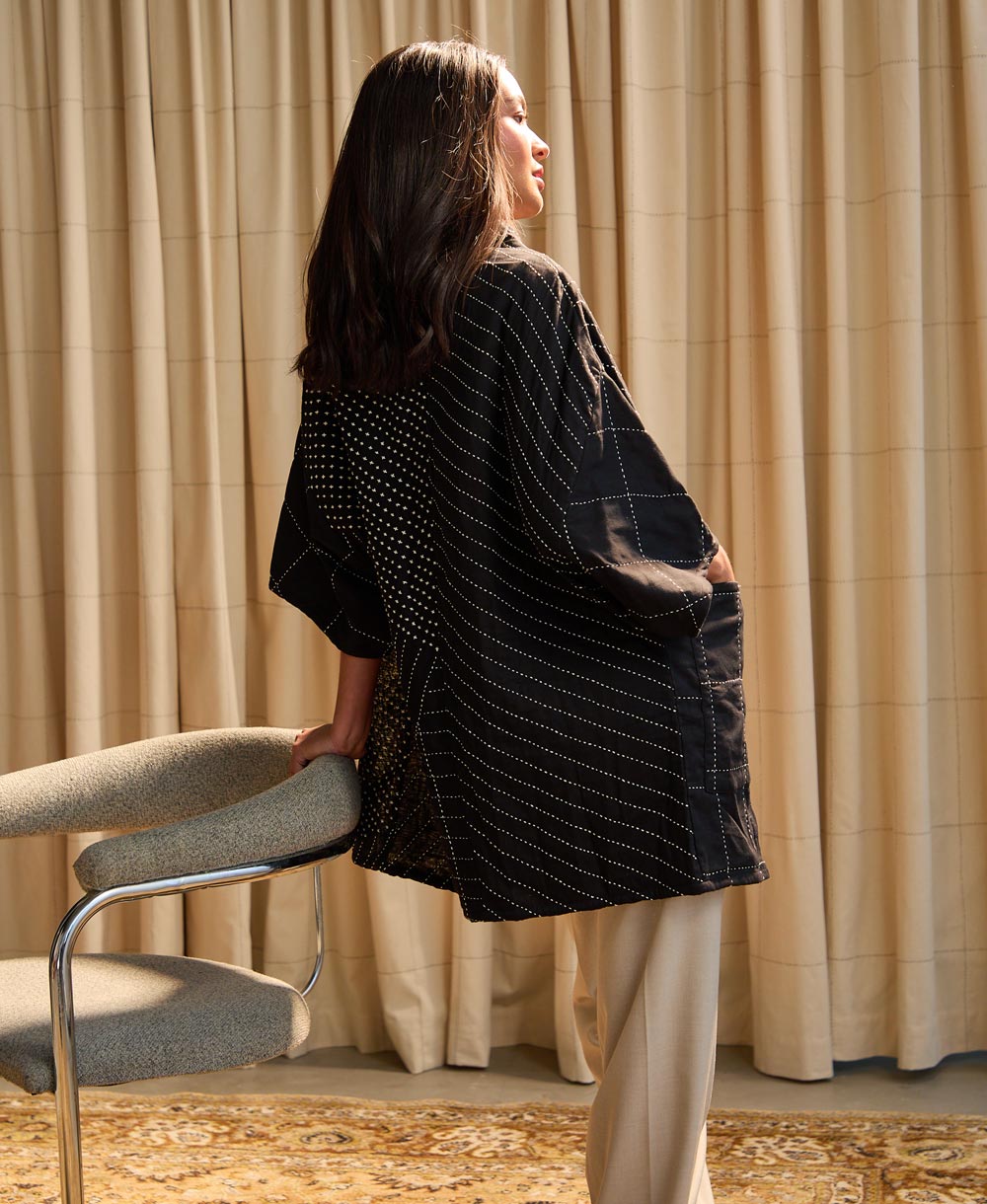 the back of woman standing against chair in quilted black cocoon jacket