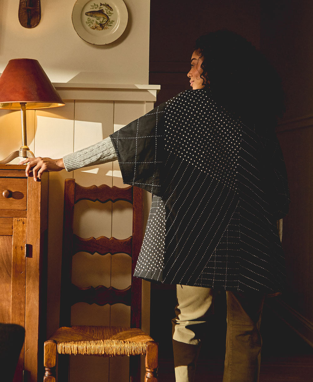 woman wearing black quilted jacket in cocoon silhouette with white embroidery pattern