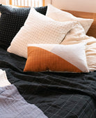 Collection of pillows and a quilt on a bed with a neutral color scheme
