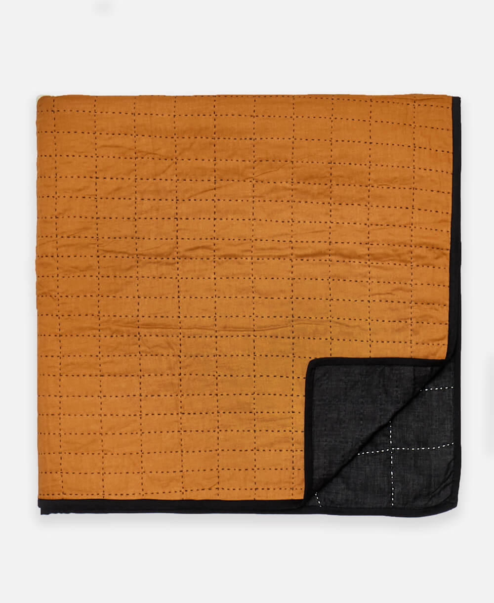 folded modern patchwork quilt with camel and black paneling and black kantha stitching