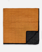 folded modern patchwork quilt with camel and black paneling and black kantha stitching
