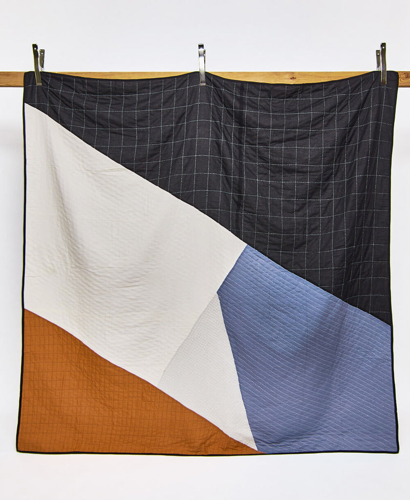 modern patchwork quilt bedding with bold angle colorblocks of black, camel and blue