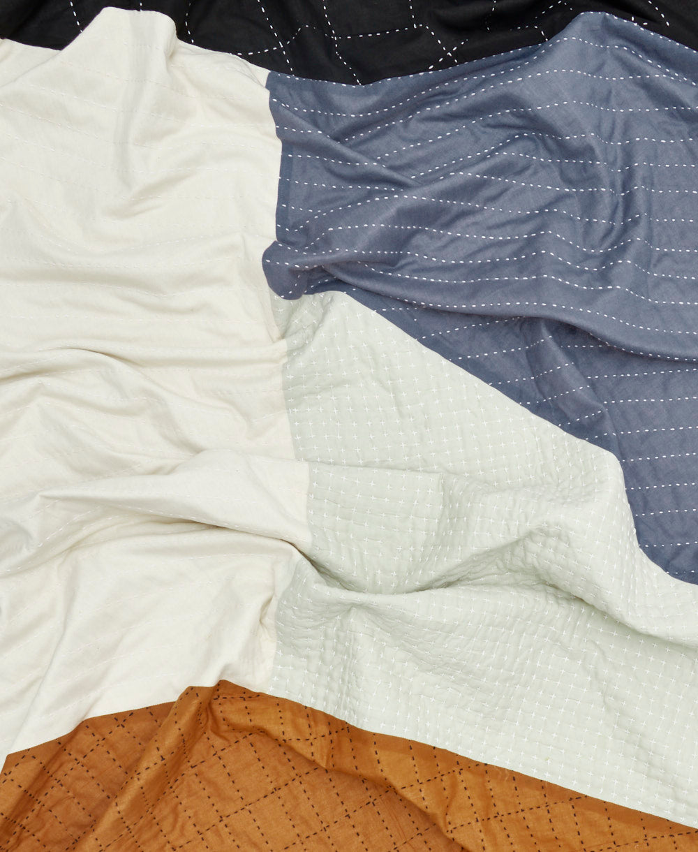 modern patchwork quilt with panels of blue, black, camel brown and ivory