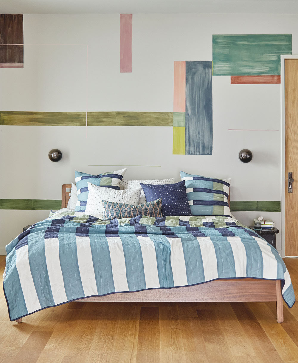 Bedroom with a bed covered in striped bedding and abstract wall art