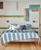 Bedroom with a bed covered in striped bedding and abstract wall art