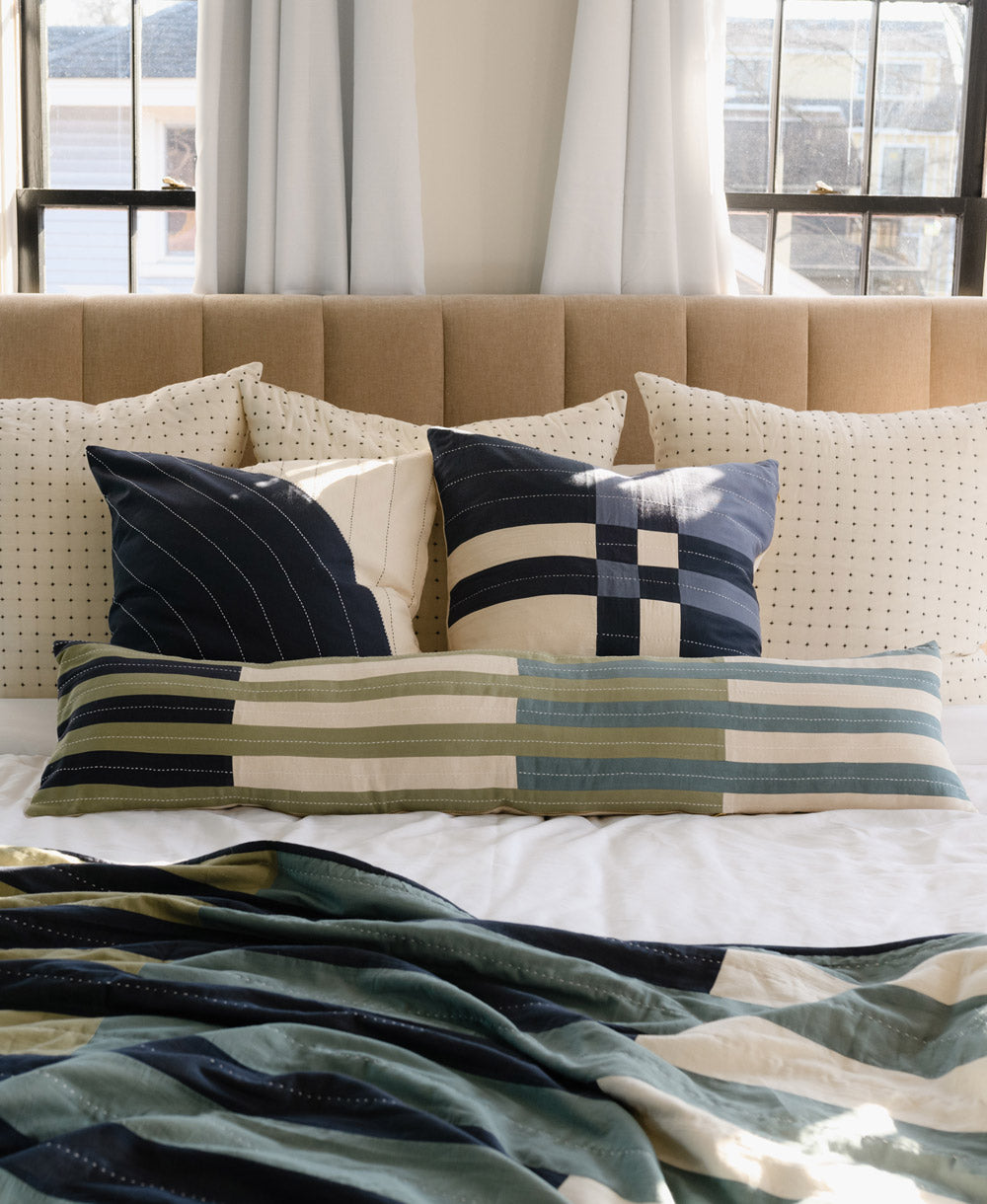 Decorative pillows on a bed with a striped blanket in a bedroom setting
