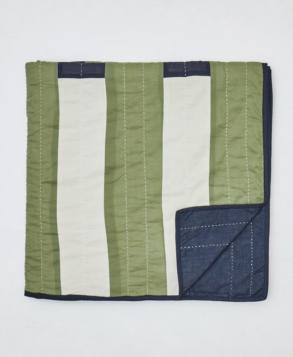 Striped quilt with green, white, and navy colors on a white background