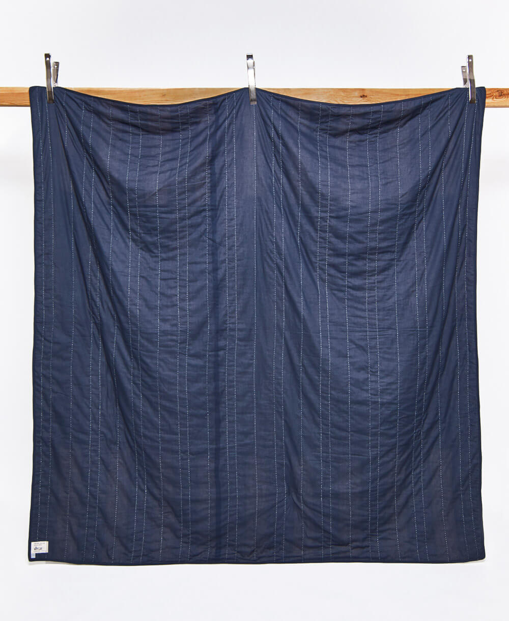 back of offset patchwork quilt in solid blue with white kantha stitching