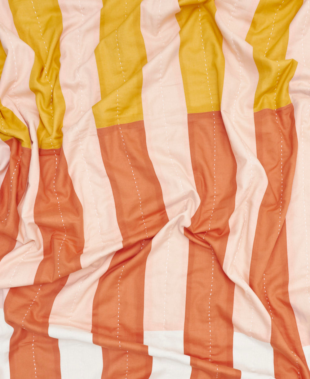Close-up of a fabric with vertical stripes in yellow, white, and orange on a white background.