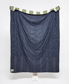 Blue striped quilt with green and white striped trim on a white background