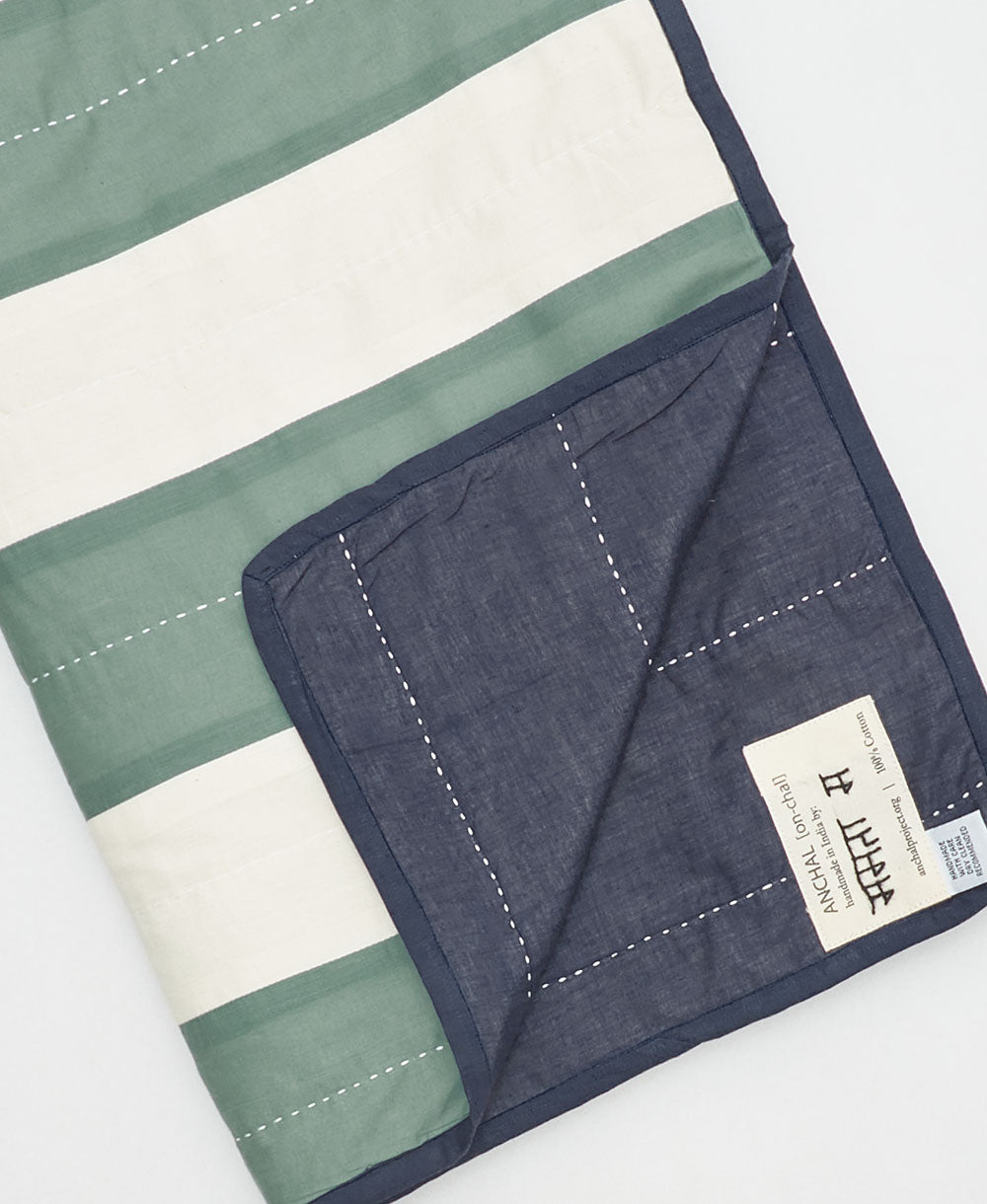 Quilt with green, white, and navy stripes on a white background