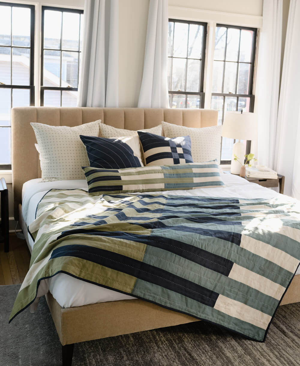 Bedroom with a bed featuring a striped comforter and pillows.