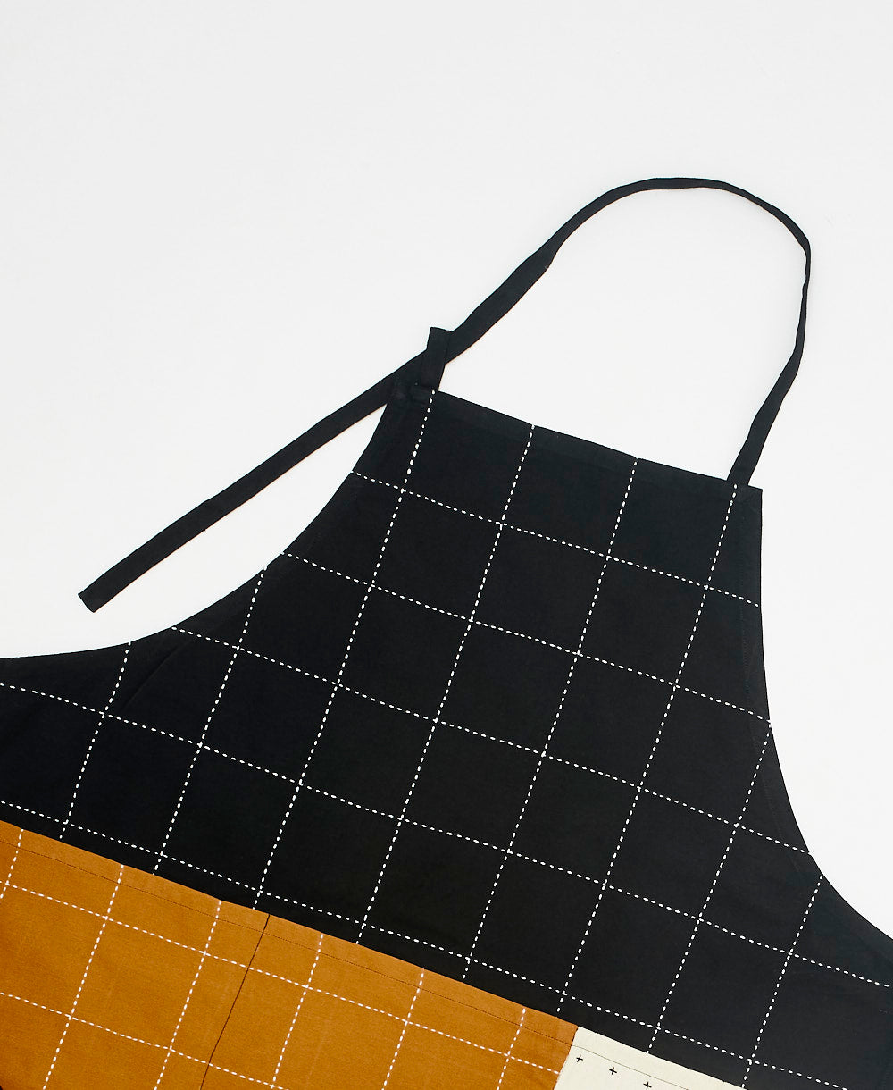 Black grid-patterned apron with brown bottom section on a white background