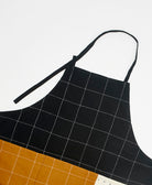 Black grid-patterned apron with brown bottom section on a white background