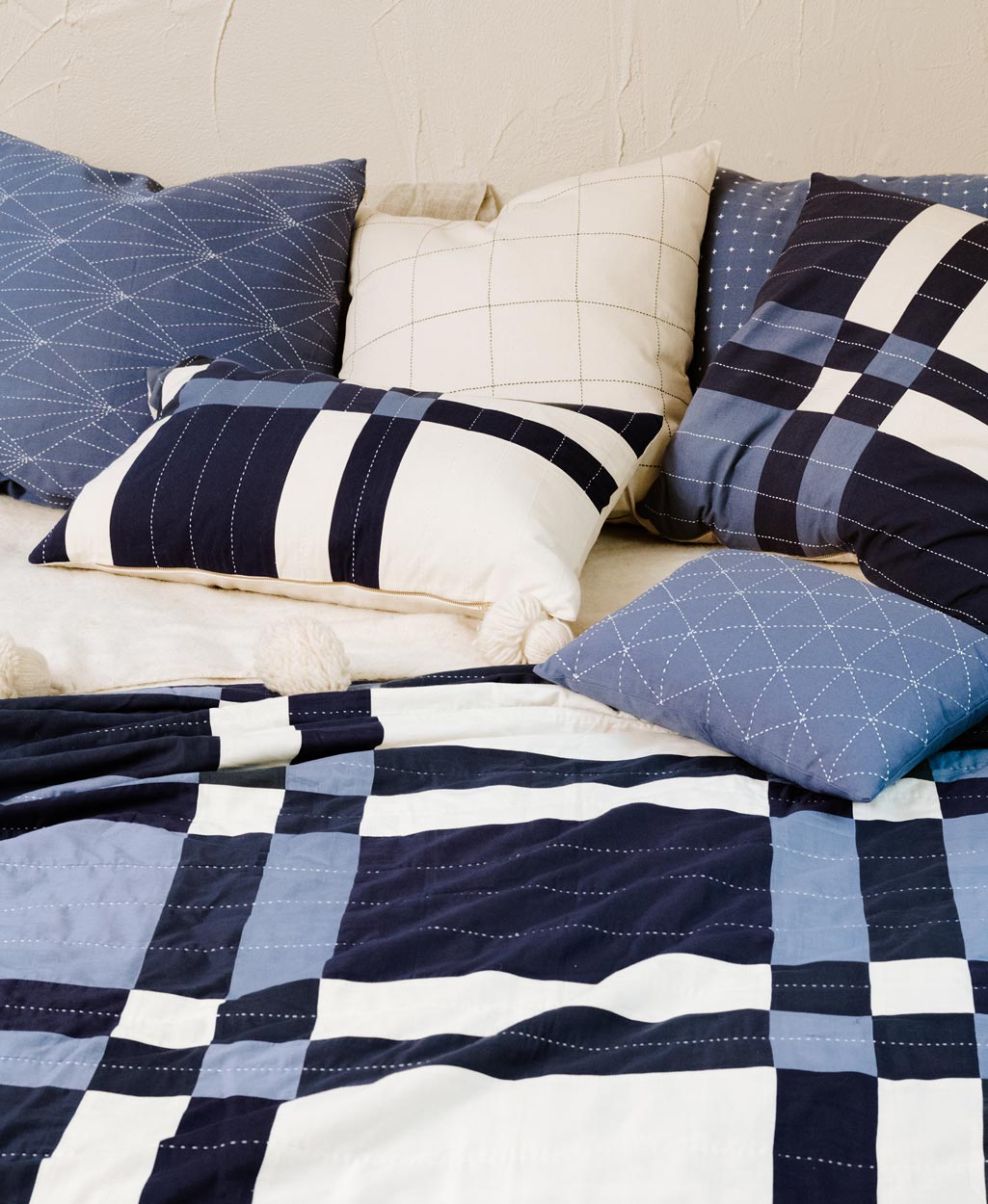 patchwork quilt with blue and white pattern on a bed with matching pillows