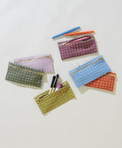 Set of colorful polka dot pencil cases with pens on a light background