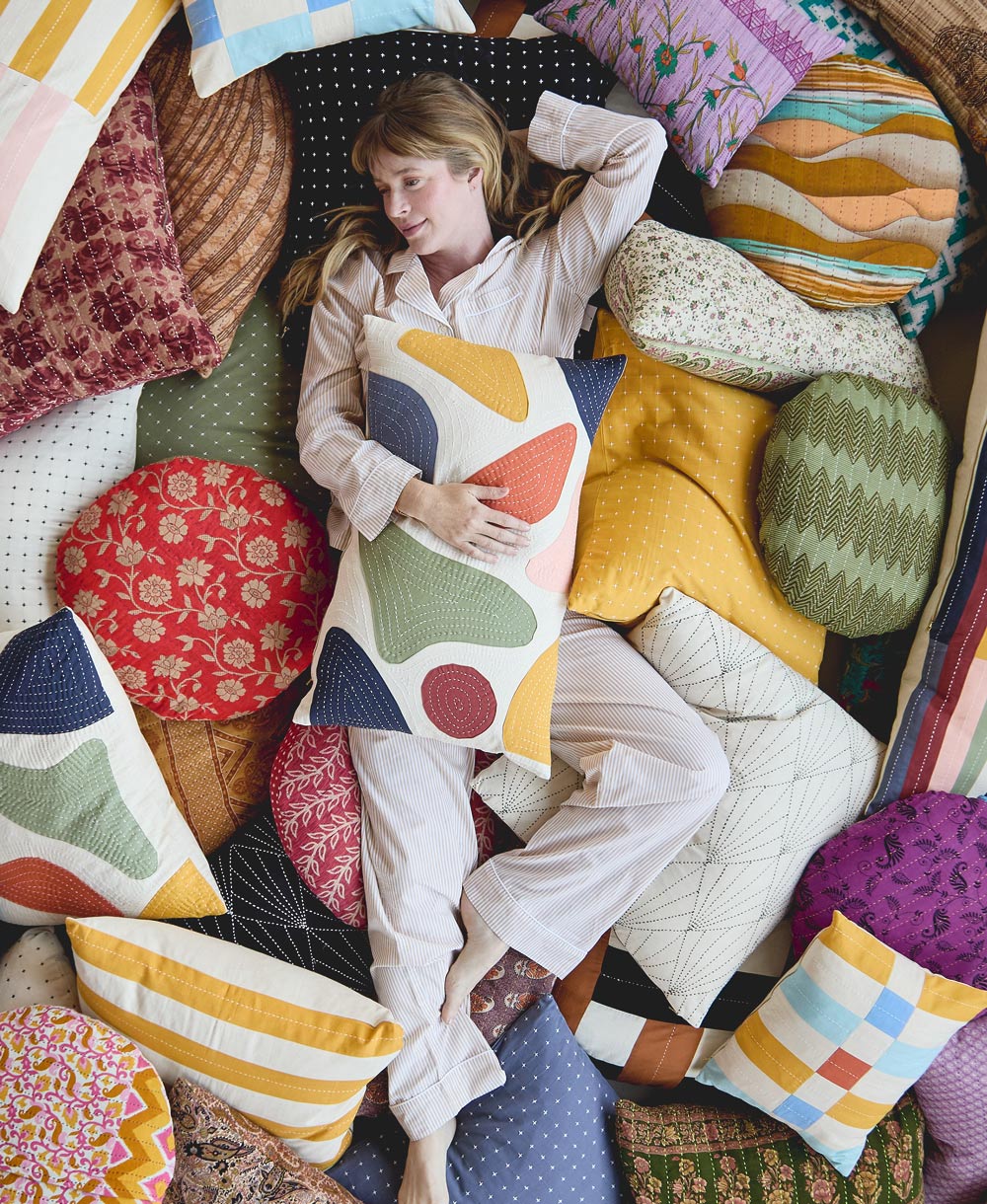 Woman lying among colorful pillows with a variety of patterns