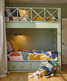 Children's bedroom with a green bunk bed featuring colorful bedding and toys on a wooden floor