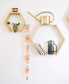 Decorative wall with hexagonal shelves holding a watering can, books, and a small plant