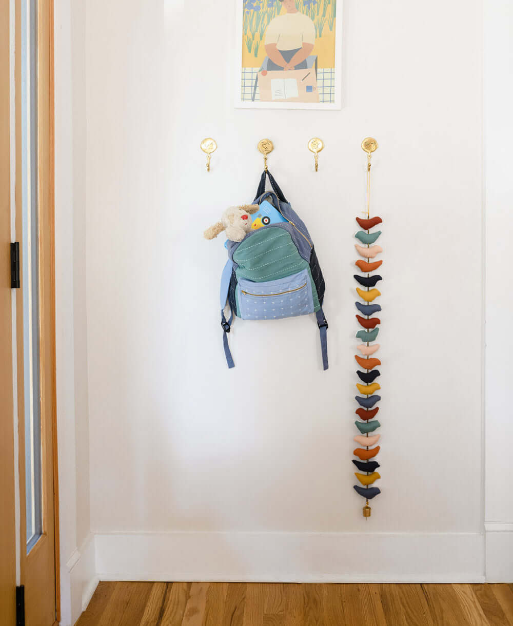 Backpack hanging on a hook with a colorful hanging organizer in a hallway