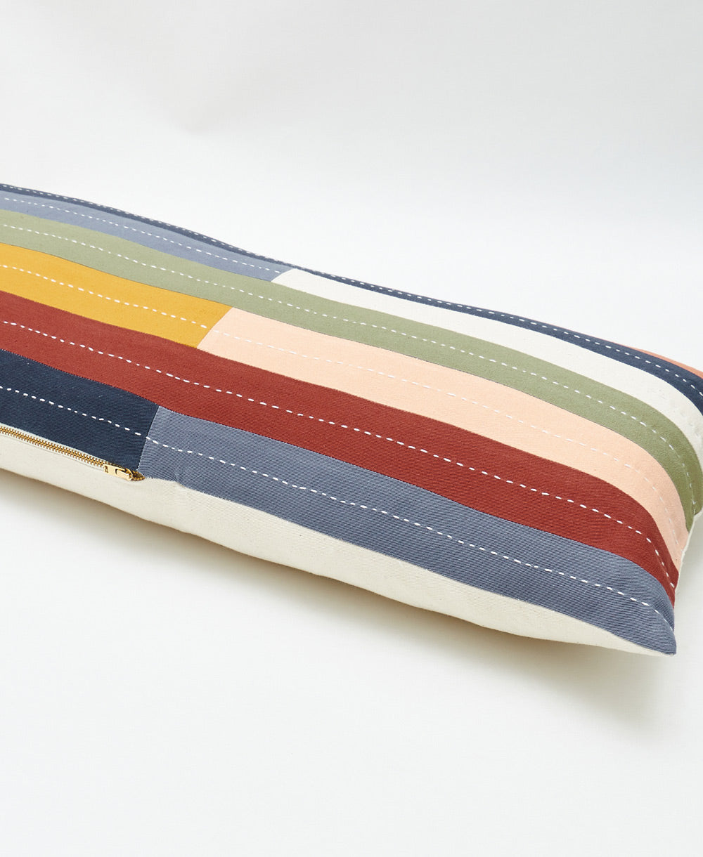 Colorful striped long lumbar pillow with a brass zipper on a white background
