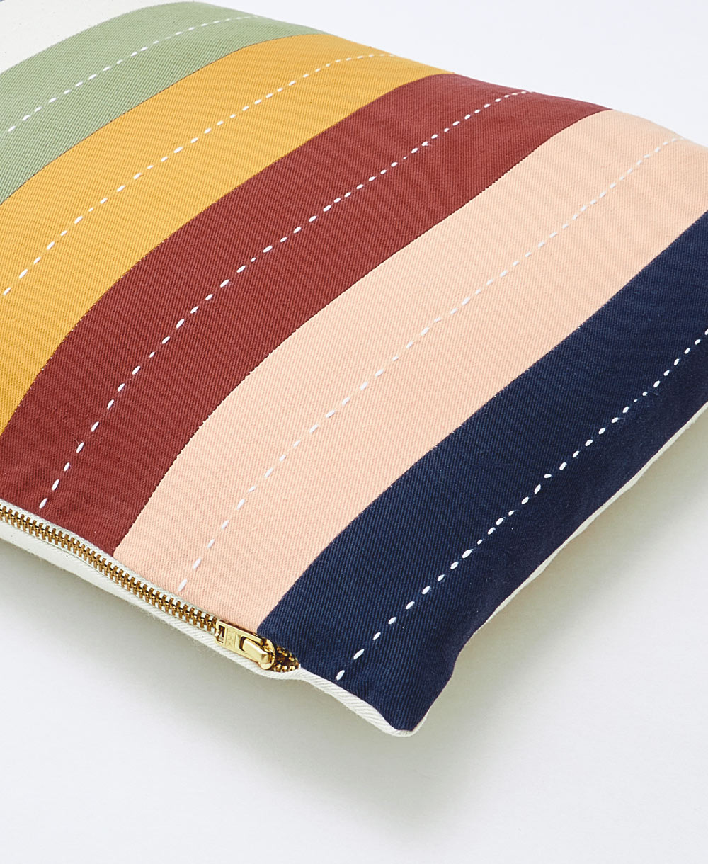 striped small pillow with vertical rainbow stripes with a brass-toned zipper