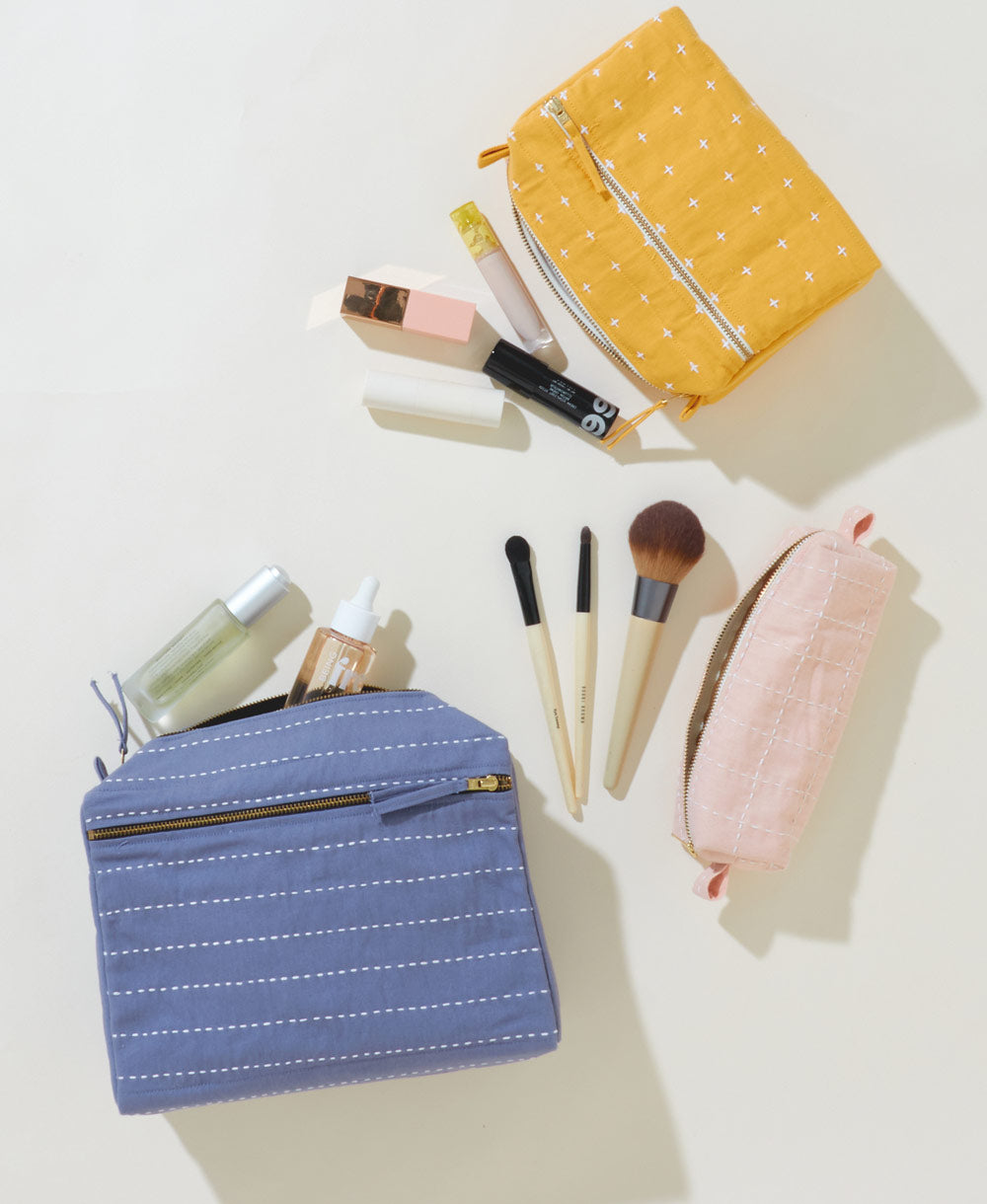 set of three different sized and colored makeup bags with different embroidery patterns on each