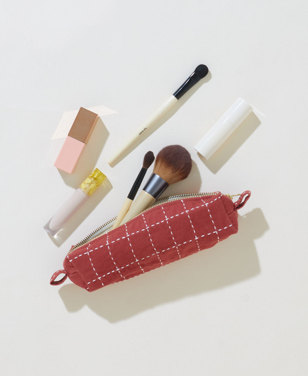 grid-stitch toiletry bag in a small size with makeup brushes spilling out