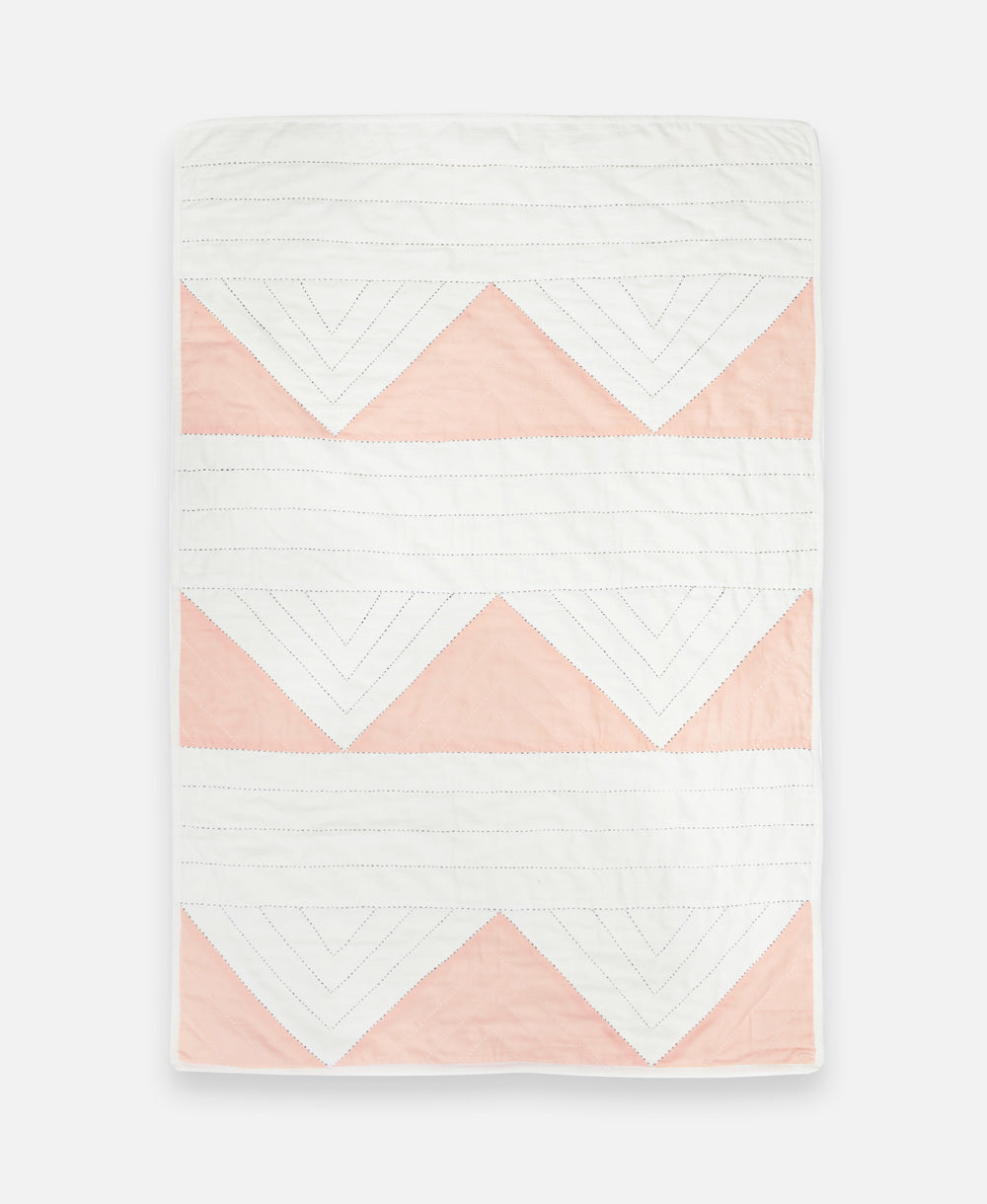 Quilt with pink and white chevron pattern on a white background