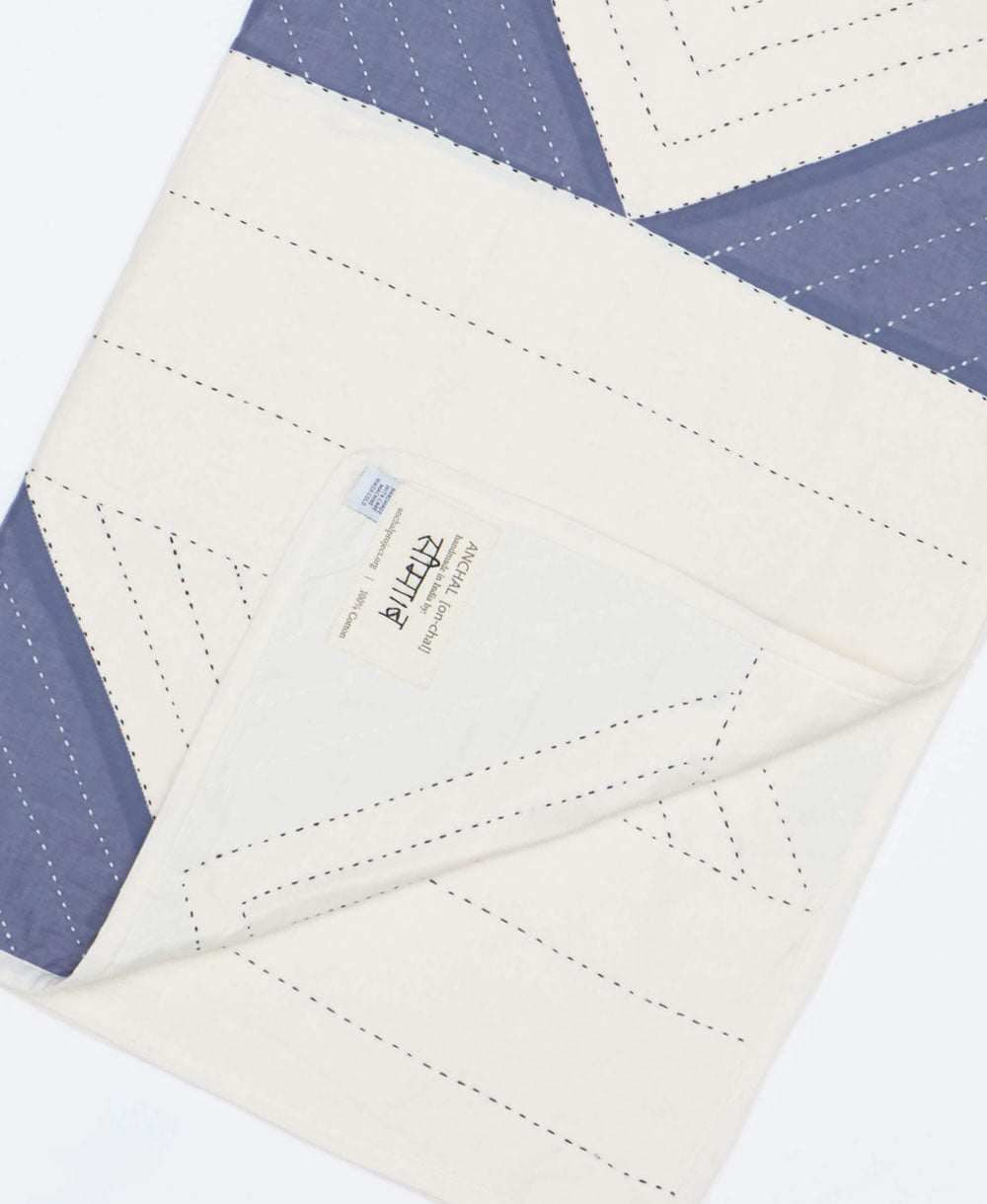 Quilted fabric with blue and white diamond pattern, featuring Anchal's artisan signed tag